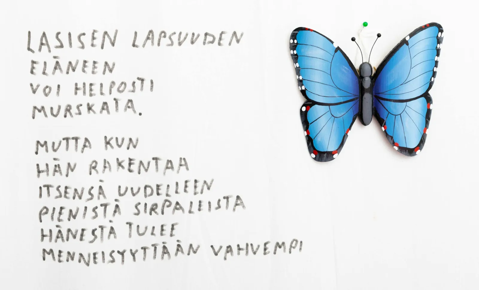Käsin kirjoitettu runo lasisesta lapsuudesta ja sininen perhonen
